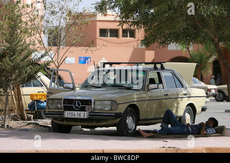 Ein gelbes Mercedes Benz Taxi parkte im Schatten unter einem Baum in der Stadt Ouarzazate, Marokko Stockfoto