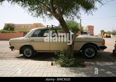 Ein gelbes Mercedes Benz Taxi parkte im Schatten unter einem Baum in der Stadt Ouarzazate, Marokko Stockfoto