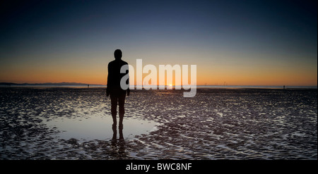 Eines Gormleyss "woanders" Skulpturen auf Crosby Strand bei Sonnenuntergang mit Offshore-Windpark in der Ferne, Liverpool Stockfoto