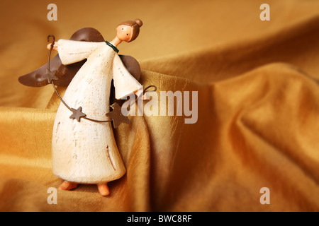 weißer antiker Christbaumschmuck Engel auf einem Hintergrund gold Stoff Stockfoto