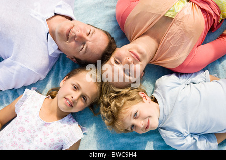 Familie einschließlich der jungen und Mädchen (8-9) liegen auf Decke, Porträt Stockfoto