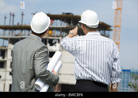 Hinten Sie Schuss von Boss zeigt auf Bau mit-Arbeiter in der Nähe von Stockfoto