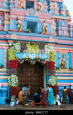 Indische Frauen dekorieren Sathya Sai Babas Gopuram Tempel Eingang mit Blumen und rangoli in der indischen Stadt Puttaparthi. Andhra Pradesh, Indien Stockfoto