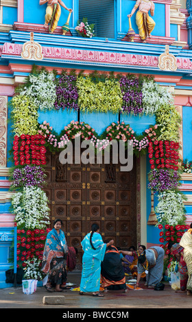 Indische Frauen dekorieren Sathya Sai Babas Gopuram Tempel Eingang mit Blumen und rangoli in der indischen Stadt Puttaparthi. Andhra Pradesh, Indien Stockfoto