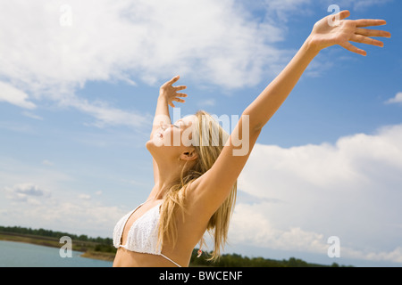 Porträt der hübsche Blondine in weißen Bikini Spaß mit ihren Augen geschlossen und hob die Arme an heißen Sommertag Stockfoto