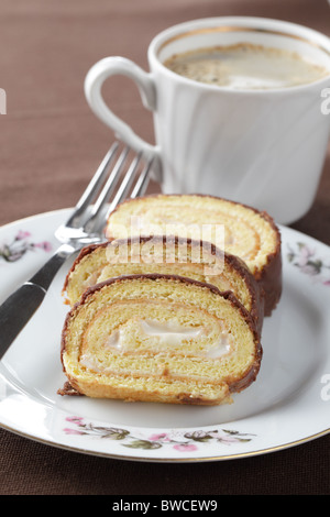 Schweizer Rolle mit Cremefüllung und Schokolade Topping gegen eine Tasse schwarzen Kaffee Stockfoto