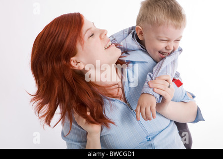 Nettes Kind umarmt seine schöne Mutter und beide lachen Stockfoto