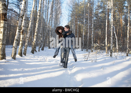 Russland, Voronezh, junger Mann geben Huckepack Fahrt Freundin im verschneiten park Stockfoto