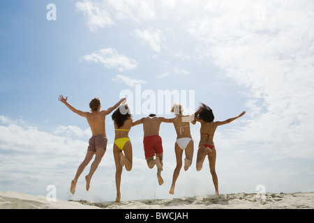 Rückansicht der Freunde halten Sie Hände und springen auf sand Stockfoto
