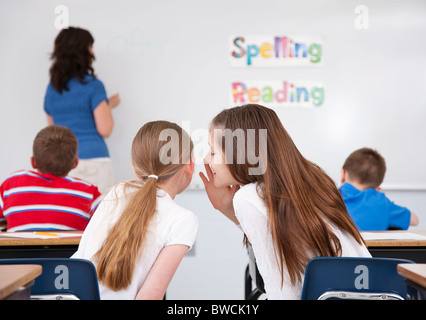 USA, Illinois, Metamora, Schulmädchen (8-9, 10-11) Flüstern im Klassenzimmer, Lehrerin am Whiteboard im Hintergrund Stockfoto