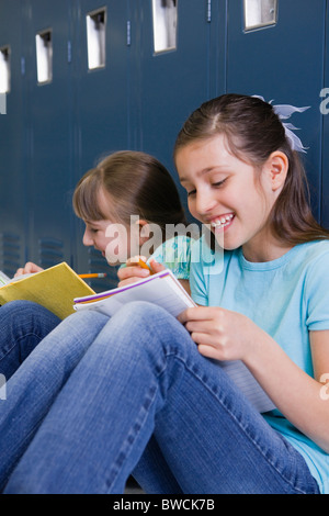 USA, Illinois, Metamora, zwei Mädchen (8-9) sitzen an Schließfächern im Flur der Schule und Hausaufgaben