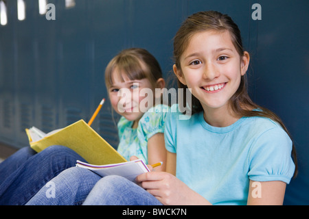 USA, Illinois, Metamora, Porträt von zwei Mädchen (8-9) sitzen an Schließfächern im Flur der Schule und Hausaufgaben
