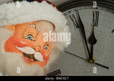 Der Weihnachtsmann lächelt mit einer großen Uhr im Hintergrund, die sich der Mitternacht nähert Stockfoto