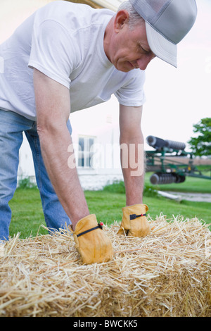 USA, Illinois, Metamora, Landwirt anhebende Heuballen auf Bauernhof Stockfoto