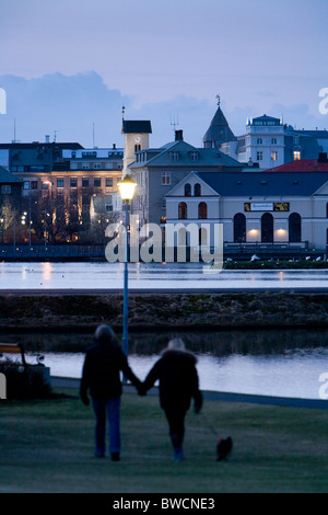 Menschen zu Fuß entlang Tjörnin-Sees. Die Innenstadt von Reykjavik, Island. Stockfoto