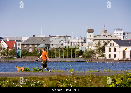 Mann geht seinen Hund Tjörnin See. Reykjavik Island Stockfoto