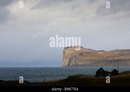 Haus außerhalb des Dorfes Hofsos, Nordwesten Islands. Thordarhofdi Kap im Hintergrund. Stockfoto