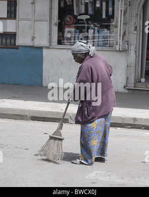 Eine alte afrikanische Frau fegt die Straße in Arusha, Tansania. Stockfoto