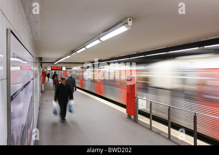 Eine lange Belichtung eines der Plattformen in der Rathaus-U-Bahn Station in Hamburg, fahrenden Zug und Menschen zeigen. Stockfoto