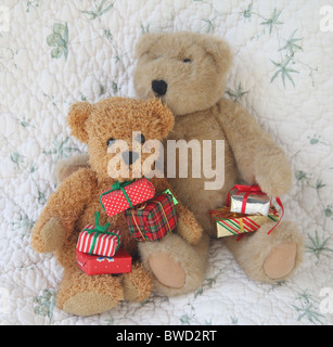 zwei alte Spielzeug-Bären mit bunt verpackte Weihnachtsgeschenke gegen einen quilt Stockfoto