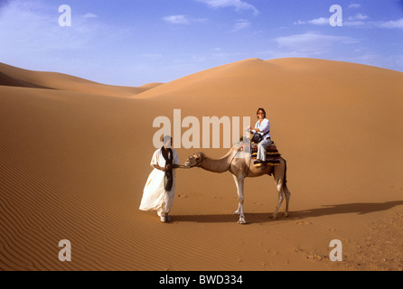 Frau sitzt auf Kamel mit Berber Führer, Wüste Sahara, Merzouga, Marokko, Nordafrika Stockfoto