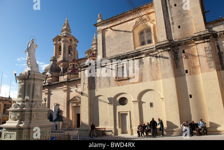 Rentner sitzen auf den Bänken auf dem Marktplatz vor der Kirche von Zurrieq in Malta. Stockfoto