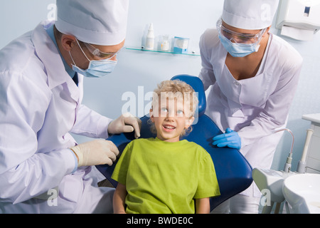 Bild des netten jungen im Gespräch mit Zahnarzt und seine Assistentin vor Mund-checkup Stockfoto