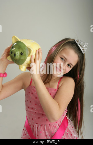 Zehn Jahre altes Mädchen ein Sparschwein in ihren Händen hält. Stockfoto