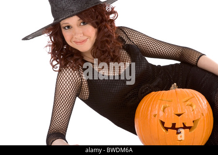 Porträt von Hispanic Teenager Mädchen in schwarz Halloween Hut und Netzstrümpfe Kleid mit geschnitzten Kürbis (Jack o ' Lantern) Stockfoto