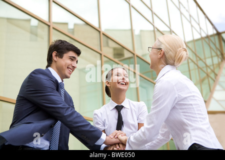 Konzeptionelle Darstellung der Menschen halten Hände übereinander und lachen Stockfoto