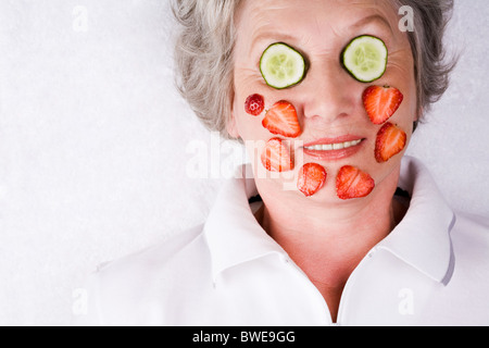 Gesicht der reifen Frau mit Gurke und Erdbeere Scheiben drauf Stockfoto