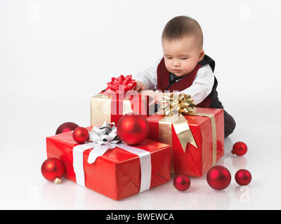 Sechs Monate altes Baby junge Weihnachtsgeschenke zu öffnen. Isoliert auf weißem Hintergrund. Stockfoto