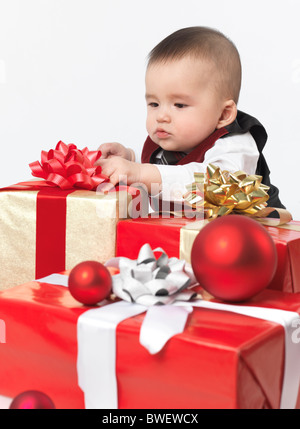 Sechs Monate altes Baby junge Weihnachtsgeschenke zu öffnen. Isoliert auf weißem Hintergrund. Stockfoto