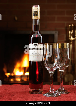 Flasche roten Eiswein Cabernet Franc von Hillebrand und zwei Weingläser auf dem Tisch mit einem Kamin im Hintergrund Stockfoto