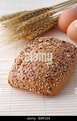 Vollkorn-Rollen liegen neben einigen Eiern und Getreide. Stockfoto