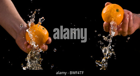 Sequenz von Orangen in der hand spritzt isoliert schwarzen Hintergrund Stockfoto