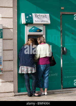 Zwei Frauen Bargeld von einem Geldautomaten von einem BNP Paribas, Frankreich Stockfoto