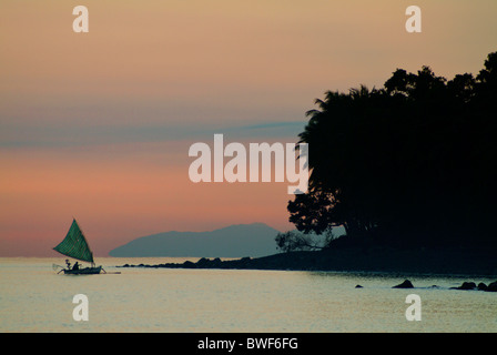 Bei Sonnenaufgang segelt ein Fischer in einem Einbaum-Kanu in Ufer, seinen Fang von einer Nacht der Fischerei auf der Insel Bali zu verlagern. Stockfoto