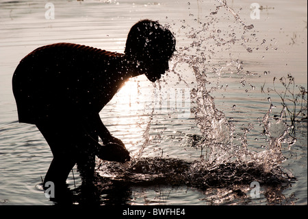 Indischer junge Trinkwasser und Waschen in einem See in Indien bei Sonnenuntergang. Silhouette. Andhra Pradesh, Indien Stockfoto