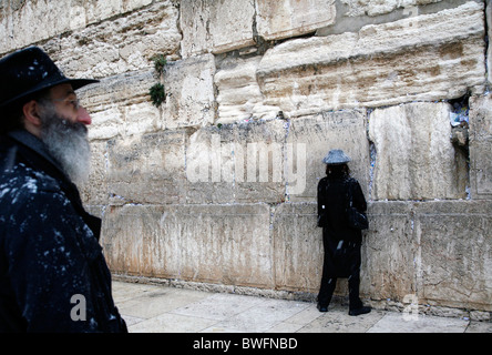 Religiöse Juden beten an der Klagemauer in Jerusalem im Schnee. Stockfoto