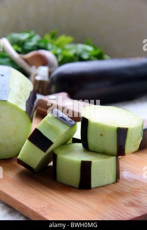 Auberginen in Scheiben geschnitten und auf einem Holzbrett gereinigt Stockfoto