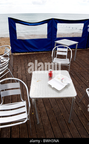 England West Sussex Bognor Regis Empty Aluminium Chairs und Tabellen auf Holzterrassen hinter einer Wind-Pause am einsamen Strand Stockfoto