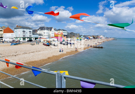 England West Sussex Bognor Regis Schindel Kiesstrand und direkt am Meer mit Touristen durch bunte Fahnen auf Pier gesehen Stockfoto