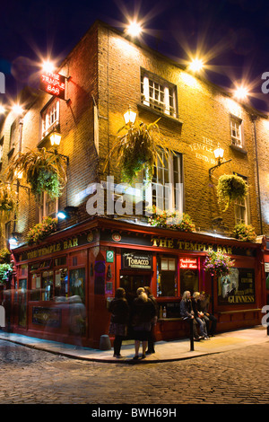 Irland County Dublin City Temple Bar Pub mit Passanten vorbei auf der gepflasterten Straße in der Nacht beleuchtet Stockfoto