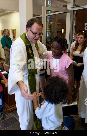 Anglo männlichen Pastor begrüßt junge Afro-amerikanische Gemeindegliedern, wie Gemeinde reiht sich nach dem sonntäglichen Gottesdienst verlassen Stockfoto