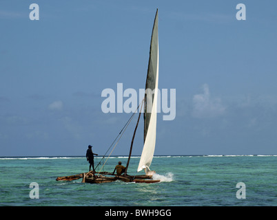 Lokale outrigger Fischerboot oder ngalawa (dhau) Segeln Matemwe Sansibar mit einem crewman Outrigger aufrecht stehend auf Segel und Mast zu bringen Stockfoto