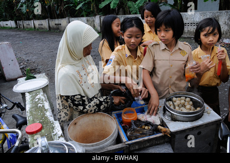 Schülerinnen und Schüler in Schuluniform in der Pause vor der Schule an einem muslimischen Hawker, Yogyakarta, Zentral-Java, Java, Indonesien Stockfoto