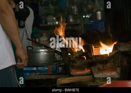 Ein männlicher Koch macht Frühstück für Food-Kunden auf einen Holzofen in einem Restaurant in Mae Hong Son, Thailand. Stockfoto