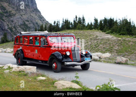 Rote Tour-Bus mit Menschen in Fahrt im Glacier National Park, Montana Stockfoto