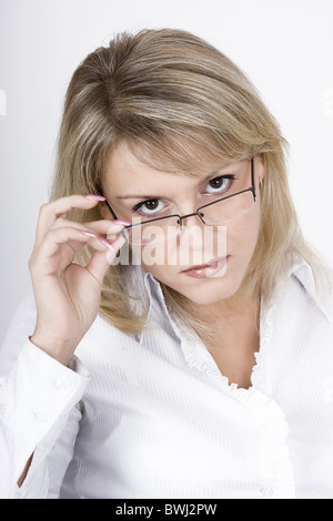 Die strengen Blondine in Gläsern auf einem hellen Hintergrund Stockfoto